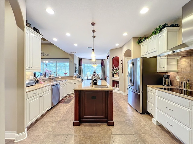 kitchen featuring sink, white cabinetry, decorative light fixtures, wall chimney exhaust hood, and a kitchen island with sink