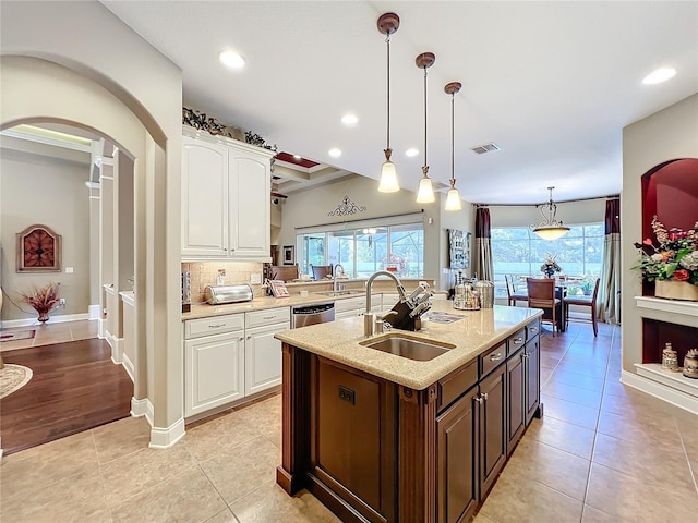 kitchen featuring a center island with sink, sink, hanging light fixtures, and white cabinets