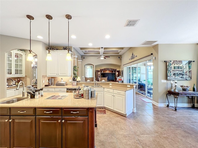 kitchen with a kitchen island with sink, sink, ceiling fan, white cabinets, and pendant lighting