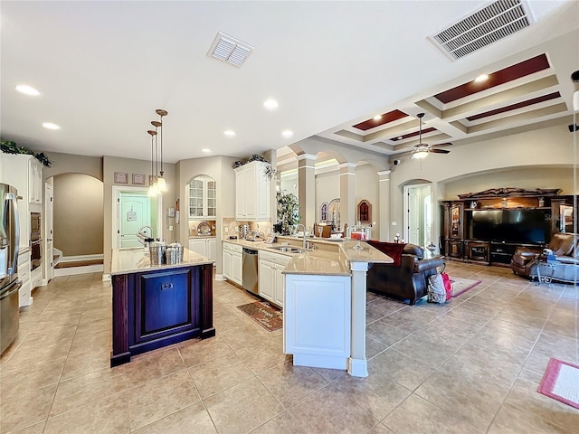 kitchen featuring coffered ceiling, appliances with stainless steel finishes, sink, hanging light fixtures, and an island with sink