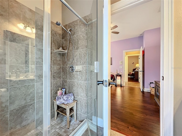 bathroom with hardwood / wood-style floors, ceiling fan, and a shower with door