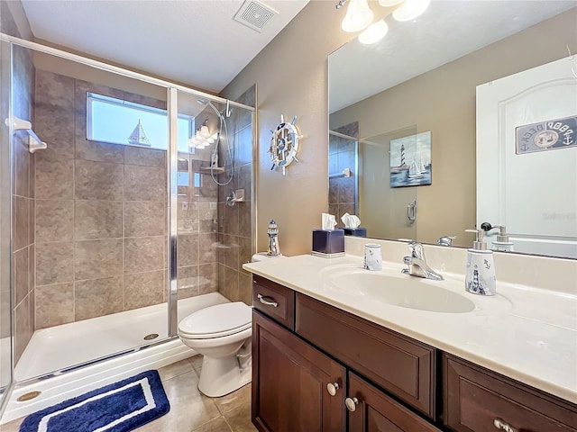 bathroom featuring tile patterned flooring, vanity, toilet, and a shower with shower door