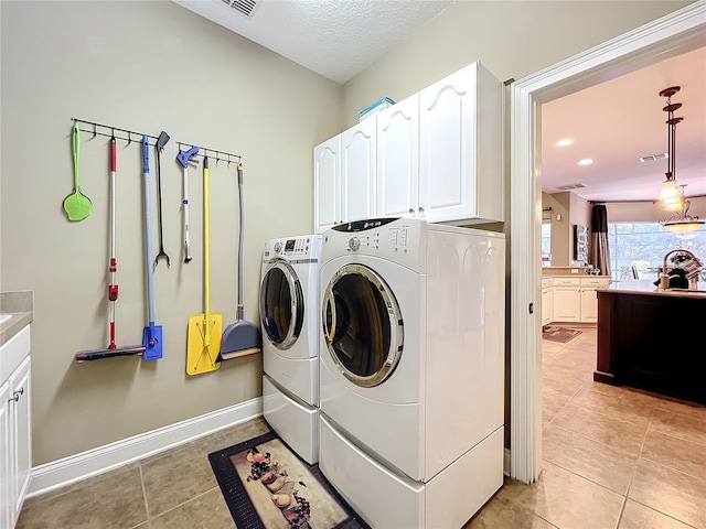 laundry room with cabinets, washer and dryer, sink, light tile patterned floors, and a textured ceiling