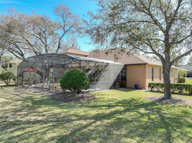 back of property with a yard and glass enclosure