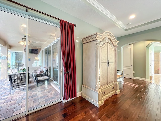 corridor featuring a raised ceiling, crown molding, and dark hardwood / wood-style floors