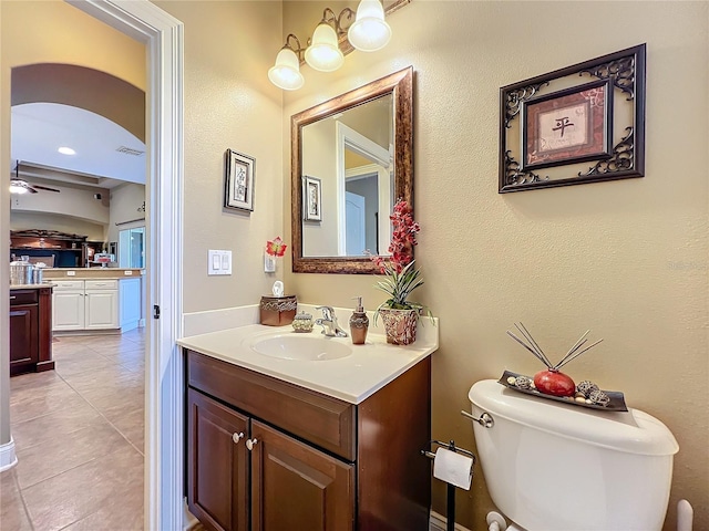 bathroom with tile patterned floors, toilet, vanity, and ceiling fan