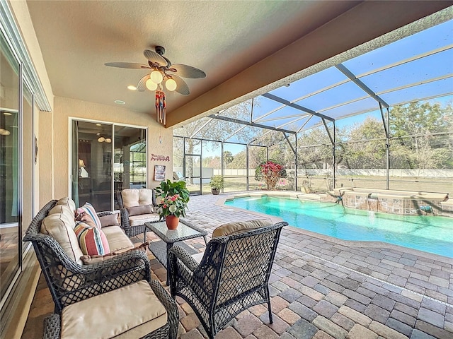 view of pool featuring a patio area, glass enclosure, ceiling fan, outdoor lounge area, and a jacuzzi