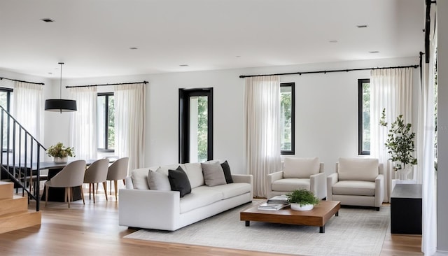 living room with a healthy amount of sunlight, stairway, and light wood finished floors