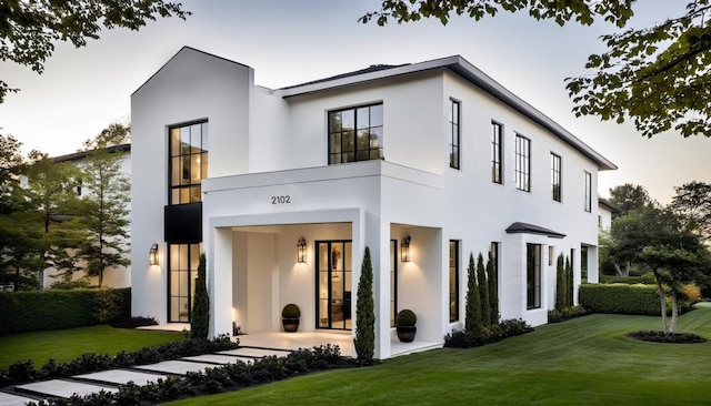 rear view of property featuring a yard and stucco siding