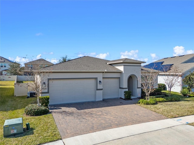 view of front of home featuring central AC unit, a garage, decorative driveway, stucco siding, and a front yard