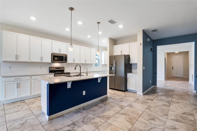 kitchen with visible vents, white cabinets, appliances with stainless steel finishes, a kitchen island with sink, and a sink