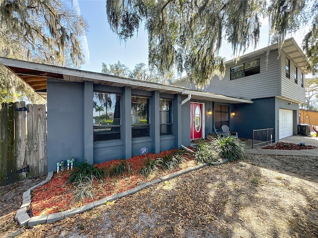 view of front facade featuring cooling unit, stucco siding, driveway, and fence