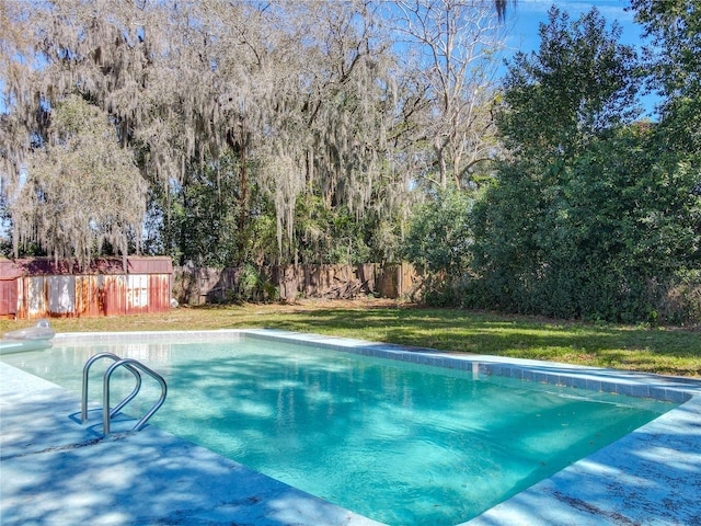 view of swimming pool featuring a lawn and fence