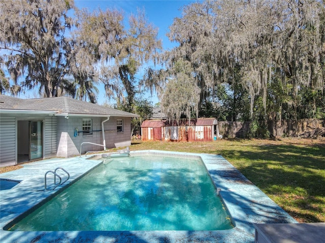 view of swimming pool with an outbuilding, a patio, a storage shed, fence, and a yard