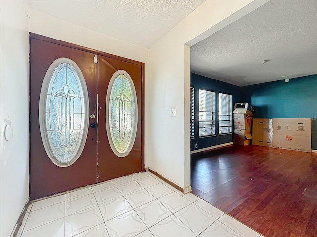 entryway with a textured ceiling, light wood-style flooring, and baseboards