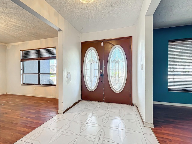 foyer with a textured ceiling, wood finished floors, and baseboards