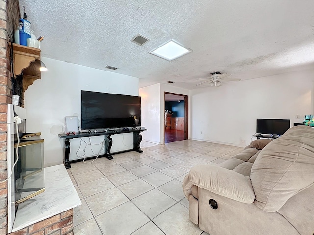 living room with a ceiling fan, visible vents, a textured ceiling, and light tile patterned floors