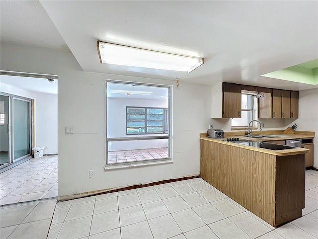 kitchen with light countertops, light tile patterned flooring, a sink, and baseboards