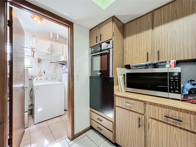 kitchen with light tile patterned floors, washer / clothes dryer, stainless steel microwave, oven, and light countertops