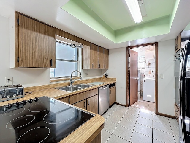 kitchen with a raised ceiling, dishwasher, washer / clothes dryer, light countertops, and a sink