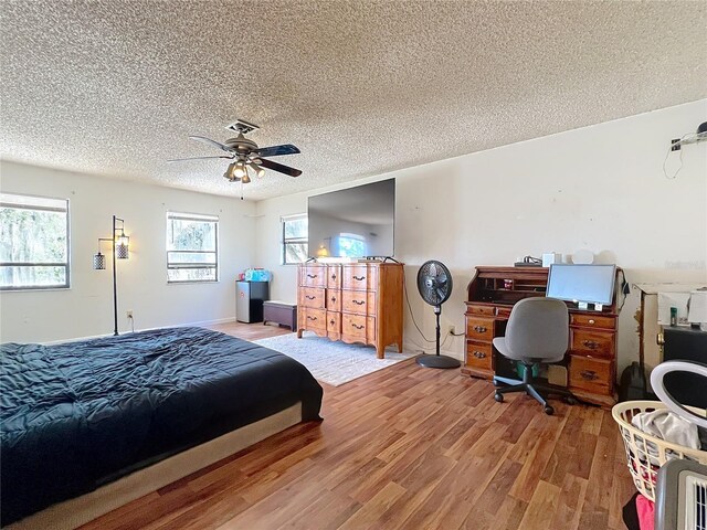 bedroom featuring baseboards, ceiling fan, a textured ceiling, and light wood finished floors