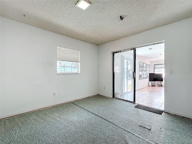 spare room with a textured ceiling, a wealth of natural light, and baseboards