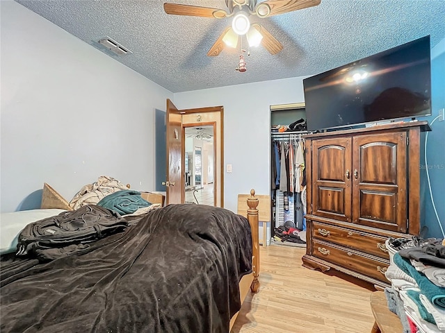 bedroom featuring a closet, visible vents, light wood-style flooring, a ceiling fan, and a textured ceiling