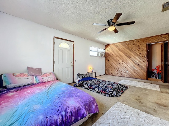 bedroom featuring a textured ceiling, carpet floors, a ceiling fan, and wooden walls