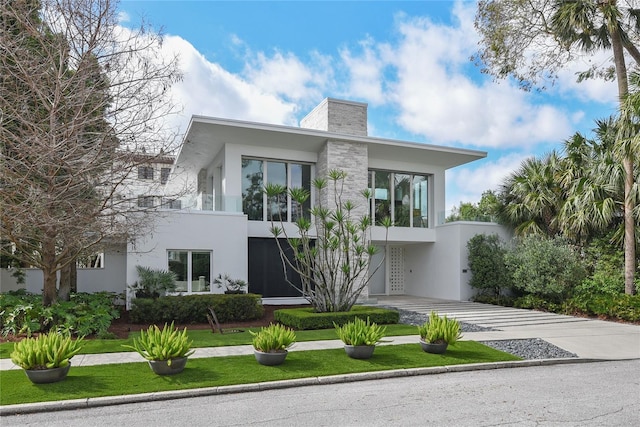 exterior space featuring driveway, a chimney, and stucco siding