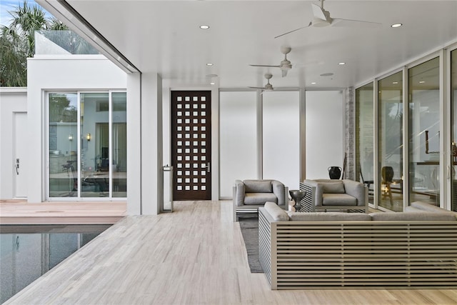 interior space with a wall of windows, wood finished floors, ceiling fan, and recessed lighting