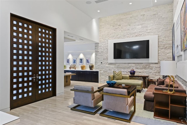 living room featuring recessed lighting, visible vents, light wood-style floors, and a towering ceiling