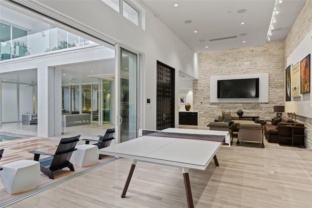 rec room with recessed lighting, light wood-style flooring, and a high ceiling