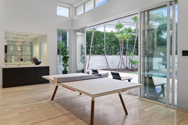 game room featuring a high ceiling and light wood-style floors