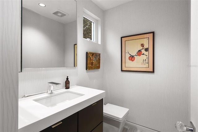 bathroom with vanity, toilet, and visible vents