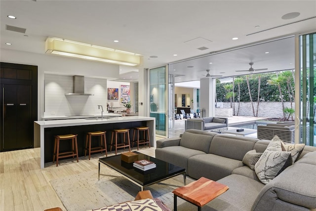 living area featuring recessed lighting, light wood-type flooring, visible vents, and expansive windows