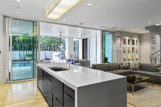 kitchen with light wood-type flooring, modern cabinets, a kitchen island with sink, expansive windows, and open floor plan