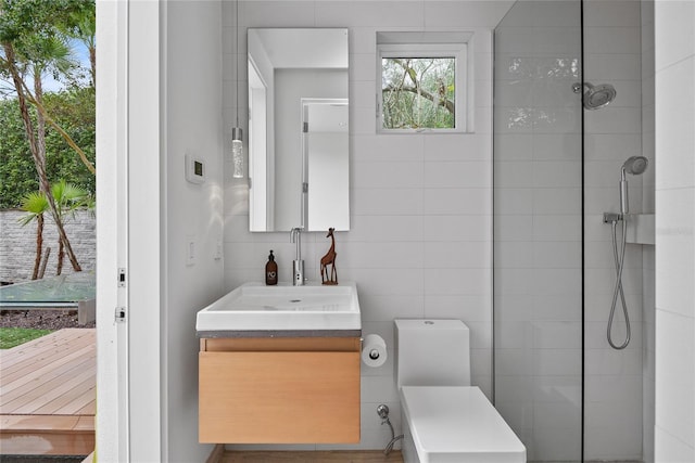 bathroom featuring tiled shower, toilet, tile walls, and vanity