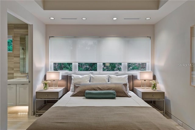 bedroom featuring recessed lighting, ensuite bath, and multiple windows