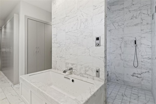 bathroom featuring a tub with jets, a marble finish shower, a sink, tile walls, and marble finish floor