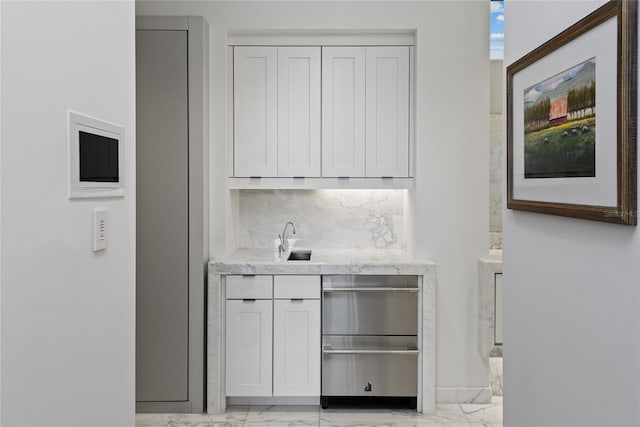 bar featuring decorative backsplash, marble finish floor, wet bar, and a sink
