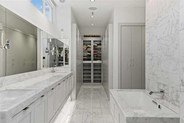 bathroom with a walk in closet, marble finish floor, a sink, recessed lighting, and a whirlpool tub