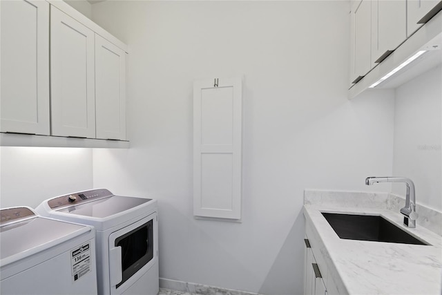 clothes washing area featuring washer and clothes dryer, cabinet space, and a sink