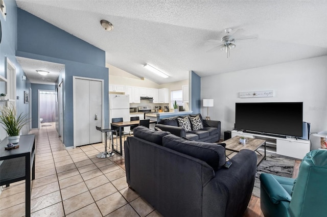 living area with lofted ceiling, light tile patterned flooring, ceiling fan, and a textured ceiling