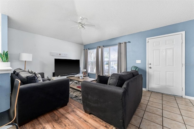 living area with a textured ceiling, light tile patterned floors, a ceiling fan, and baseboards