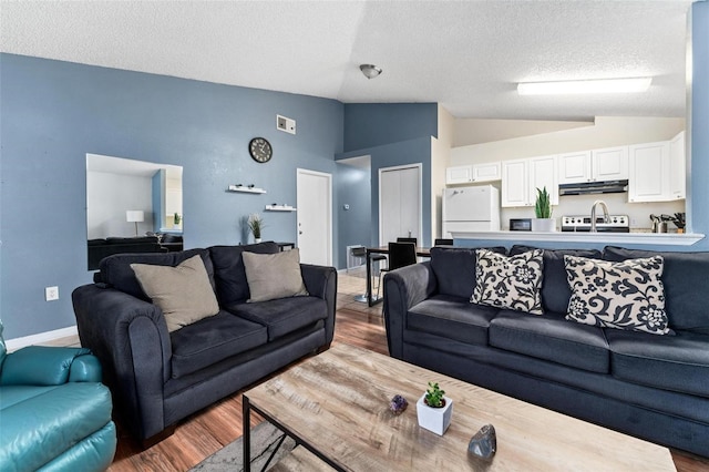 living area with vaulted ceiling, a textured ceiling, wood finished floors, and baseboards