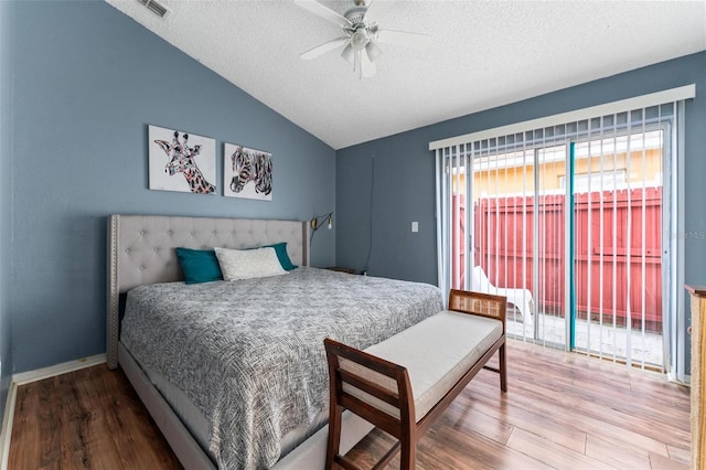 bedroom with lofted ceiling, access to exterior, a textured ceiling, and wood finished floors