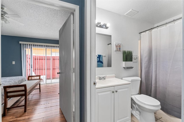 bathroom featuring a ceiling fan, toilet, wood finished floors, a textured ceiling, and vanity