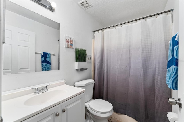 bathroom with a textured ceiling, toilet, vanity, and visible vents