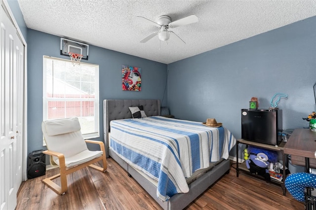 bedroom with a ceiling fan, dark wood-style flooring, and a textured ceiling