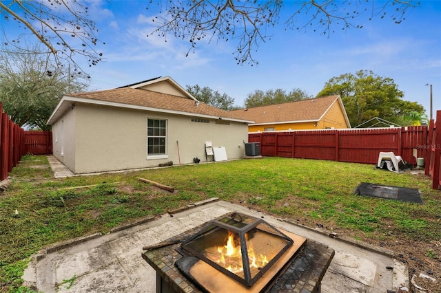 rear view of house featuring a yard, stucco siding, an outdoor fire pit, cooling unit, and a fenced backyard